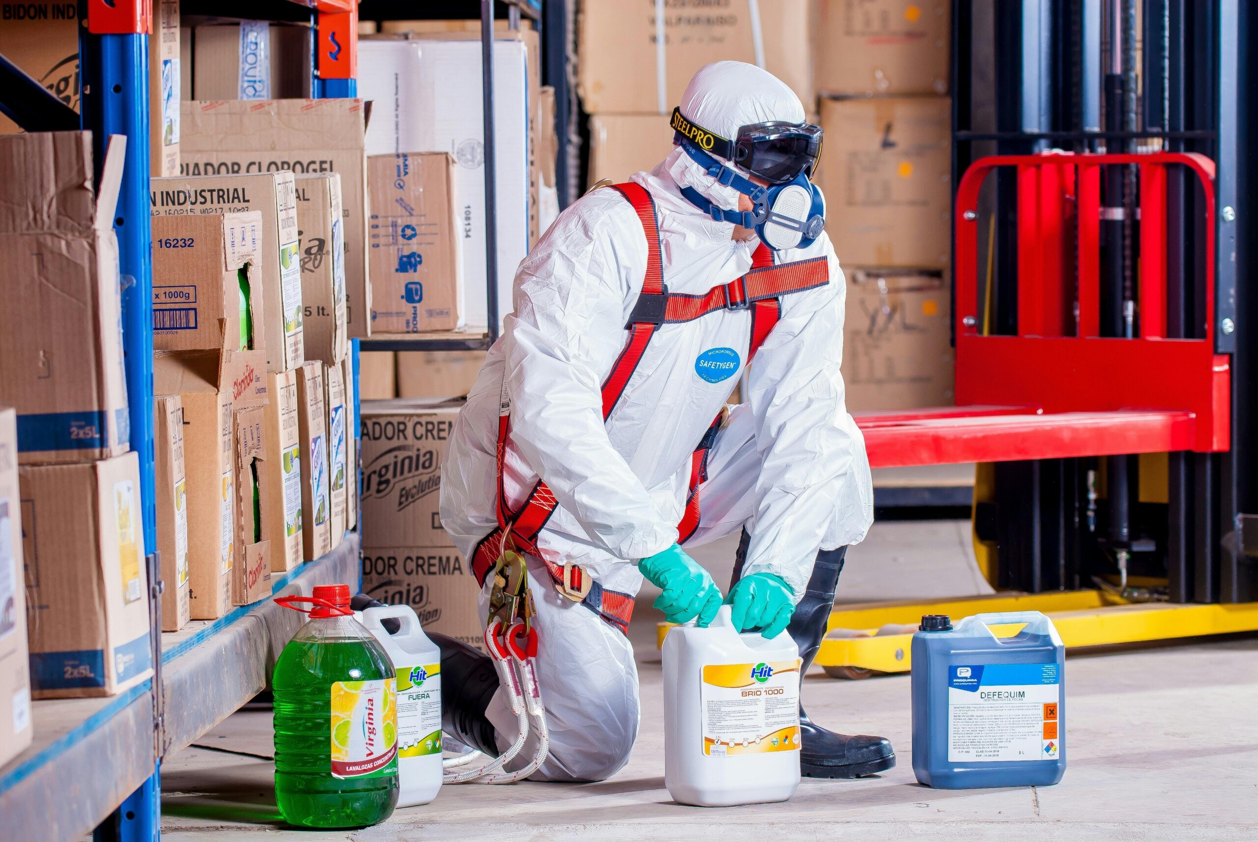 A man wearing PPE to dispose of chemical waste safely