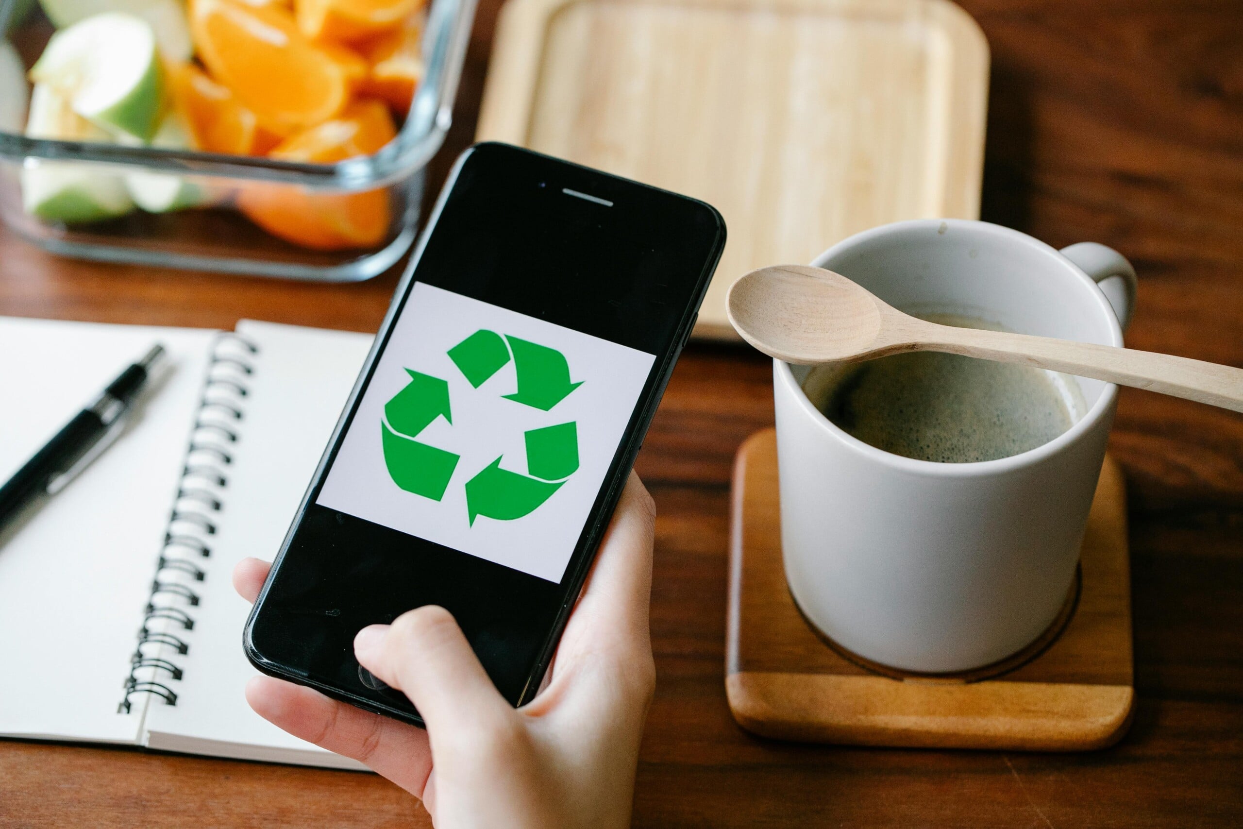 A smart phone with a recycling symbol on and a note book in the background